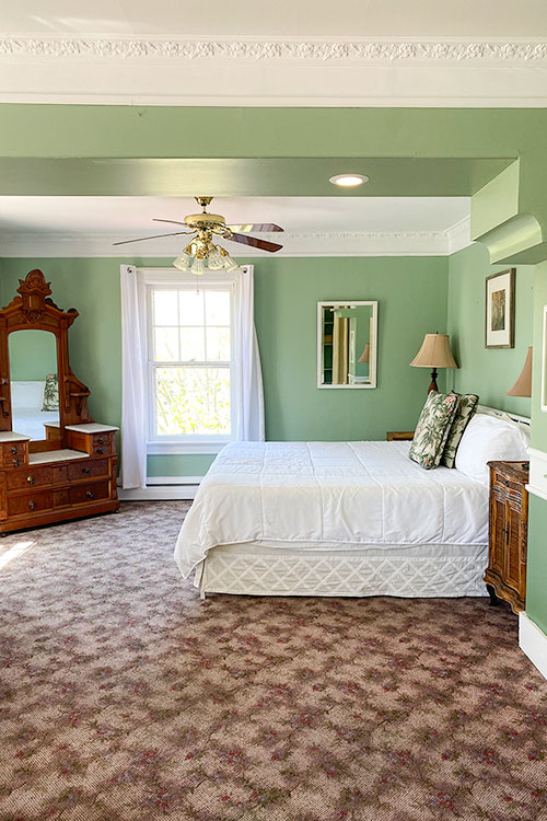 hotel room with sage green walls and a patterned carpet